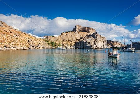 Fishing boats and sail boat in St. Paul´s bay Lindos acropolis in background (Rhodes Greece)