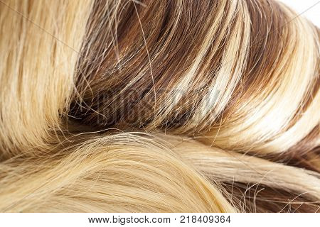 Human hair european hair weft for hair extension. Brown blonde hair texture closeup pattern. Shiny real dyed tail.