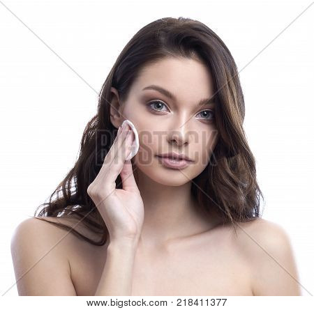 Young attractive woman cleanses the face with a cotton pad. Skincare concept. Isolated on white.