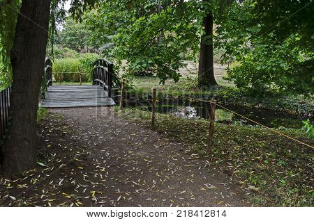 Forest, path and bridge in National monument of landscape architecture Park museum Vrana in former time royal palace on the outskirts of Sofia, Bulgaria, Europe