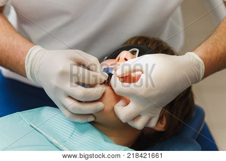Process Of Preparing And Installing Dental Ceramic Crown. Male Professional Dentist And Female Assis