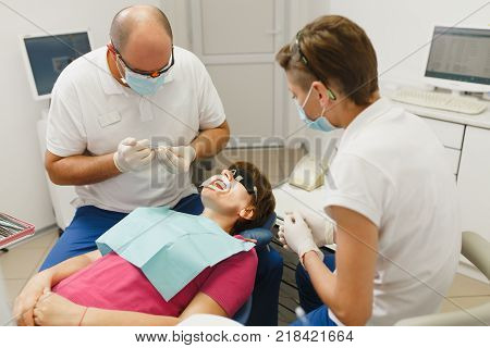 Process Of Preparing And Installing Dental Ceramic Crown. Male Professional Dentist And Female Assis