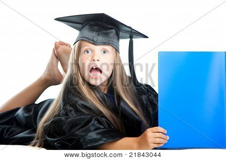 Cute little girl in laurea abito con libro blu su bianco isolato