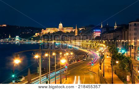 Evening view of Buda Castle with city lights and ship on the Danube river. Colorful cityscape in Budapest Hungary Europe. Artistic style post processed photo.
