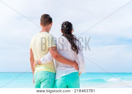 Young couple on white beach during summer vacation. Happy lovers enjoy their honeymoon at exotic island