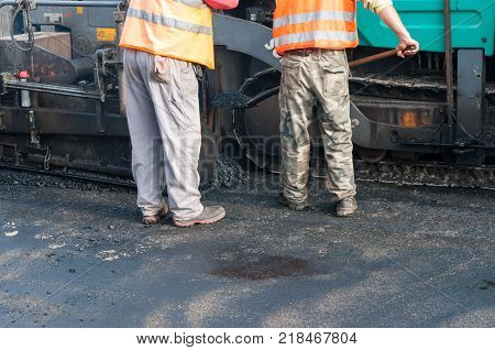 Road construction workers, asphalting machinery, road rehabilitation project in progres.