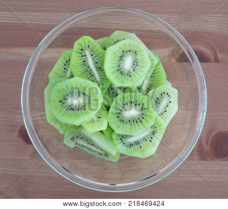 Bowl full with high in vitamins Kiwi fruit slices isolated on wooden background