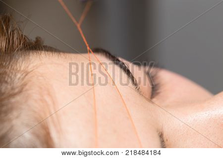 Grooming the eyebrows thread in a beauty salon. close .