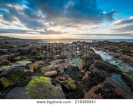 HDR dusk sunset and coastline of Scotland and Stroma. Wide angle HDR view of the rugged coastline from John O'Groats in the north of Scotland on a dusky sunset evening with the island of Stroma visible in the distance.