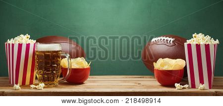 American football watching concept with pop corn and chips over green background