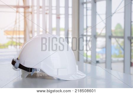 white safety helmet on desk at construction site and scaffold background engineer safety industry and construction building concept selective focus