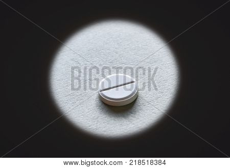 Closeup of a white tablet in the middle of dark circle