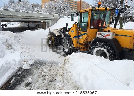 Solna Sweden - November 10 2016: Rotary brush tractor snowshoeing walking and cycling path next to Solna center.