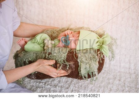 gentle hands mother. newborn child in green clothes with nipple falls asleep. the concept of childhood and motherhood