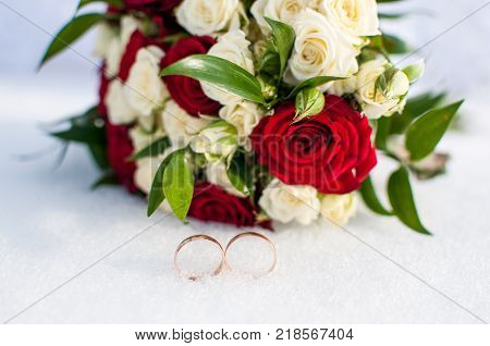 Wedding Rings And Bouquet Lying On The Snow