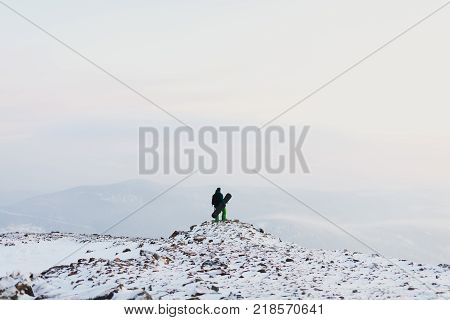 man snowboarder stands with snowboard on mountain's top. Sheregesh ski resort