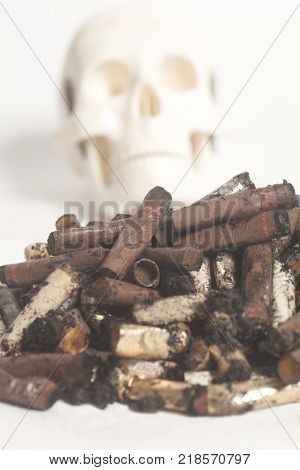 Skull and cigarette butts on white background. Smoking kills