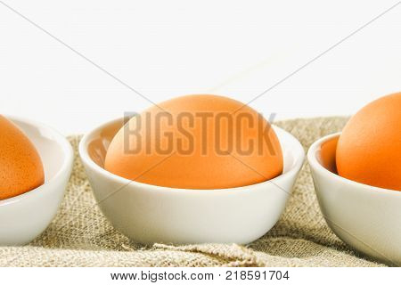Raw brown chicken eggs in glass bowls on a white wooden table. Ingredients for cooking