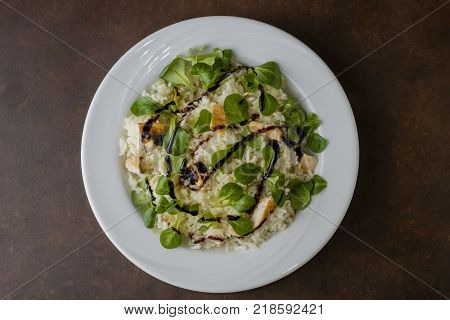 chicken and rice with valeriana salad and balsamic vinegar in a plate on wooden table