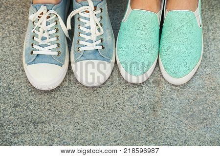 Close up view of two pairs teen's feet feet in blue sneakers