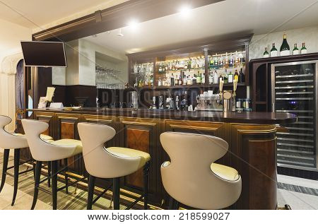 Hotel lounge bar with bottle shelves and seats. Barroom in restaurant, ready for work, copy space. Cafe background