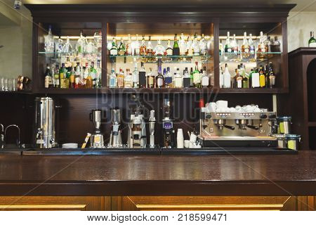 Bar counter with alcohol bottles assortment. Barroom in restaurant, hotel, pub copy space. Cafe background