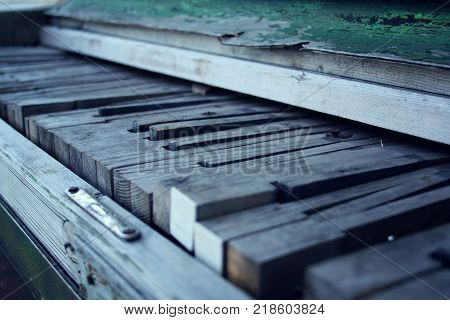 Broken piano. Aged photo. Crackling green paint on the wood. Old wooden Piano keys. Close up. Broken piano keys. Vintage filter. Decay. Old musical instrument.