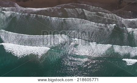 Top aerial view frop drone of Tropical exotic beach with volcanic sand in Bali, Indonesia