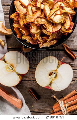 Homemade sun-dried organic apple slices crispy apple chips on an old rustic wooden table with fresh apple and cinnamon. Copy space top view