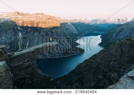 Alone tourist on Trolltunga rock - most spectacular and famous scenic cliff in Norway. Landscape photography in norwegian mountains