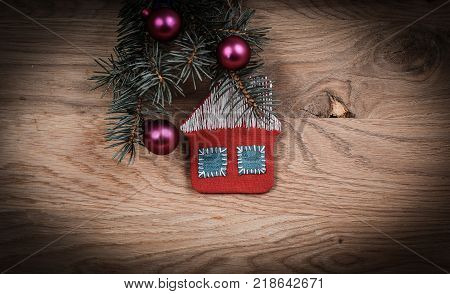 concept of Christmas.knitted house and pine branch on wooden background. place for text