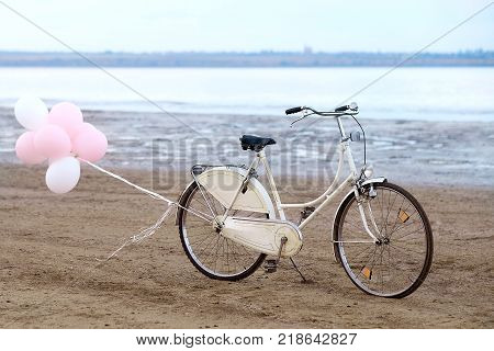Retro bike on the beach with pink balloons
