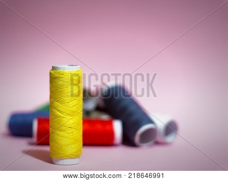 Multicolored threads on a pink background, red, blue, yellow, green