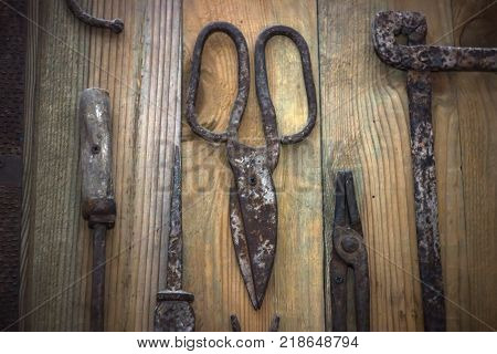 Old rusty flat-nose pliers, scissors, nails on a wooden surface, top view. Old tool.