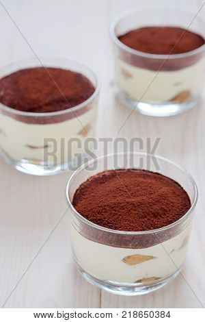 Three portions of traditional Italian dessert tiramisu on wooden table.
