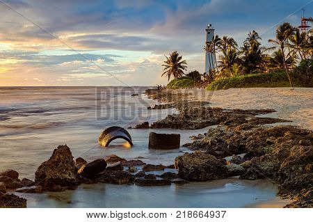 Beautiful Barbers Point Lighthouse seascape long exposure during sunset on the rocky coastline of Oahu Hawaii USA.