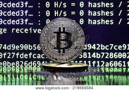 The digital process of cryptocurrency mining by using the GPUs. Bitcoins and video card on a working display and mining screen