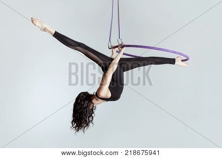 Woman aerial acrobat on the ring shows tricky tricks.