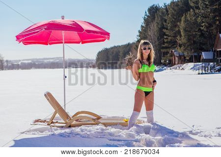 Novokuznetsk, Kemerovo region, Russia - 23 Feb, 2017 : White beaches of Siberia is an enterteiment activity where people playing beach games dressed in bikini in winter. Woman in bikini with pineapple
