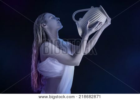 Beautiful young woman with amazing body-art as Aquarius against dark background. Zodiac signs concept