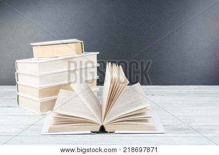 Open black and Whitel books on wooden table, black board background. Back to school. Education business concept