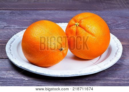 two oranges laying on a white plate