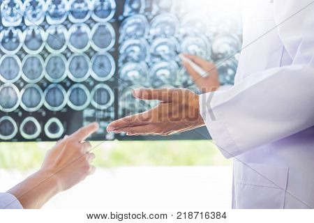 Two Doctors Analyzing A Scan Or X-ray Film Or  Explains A Ct Scan Together With Serious Thoughtful E