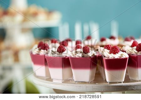 Sweet souffle decorated with raspberry and whipped cream on the blue cackground. Delicious dessert for restaurant catering or candy-bar.