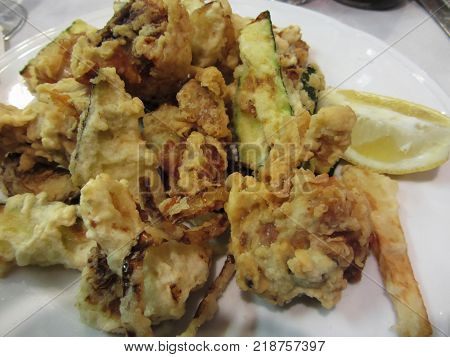 Breaded and fried crunchy vegetables with lemon slice . Battered onion rings zucchini potatoes and cauliflowers. Italian recipe