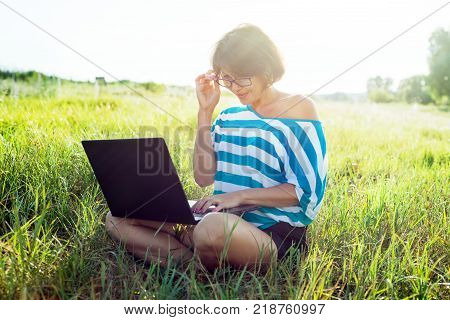 Social networking and freelance. dult woman using laptop outdoors.