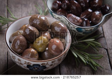 Cured, pickled or brined olive fruit on wooden table