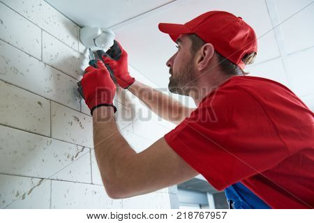 worker installing or adjusting motion sensor detector on the ceiling