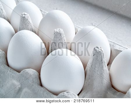 Fresh white raw eggs in shell eggs ready for cooking and diet food lie in an open cardboard container for carrying and storing eggs