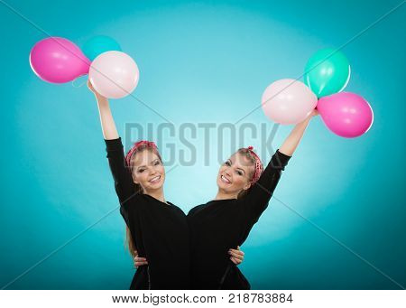 Memory of childhood and forgotten dreams. Two cute lovely retro styled women behave like little girls. Adults trying to fly away by balloons to dream come true.